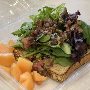 a sandwich with lettuce, salad, and fruit