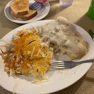 a plate of food with gravy, mashed potatoes and toast