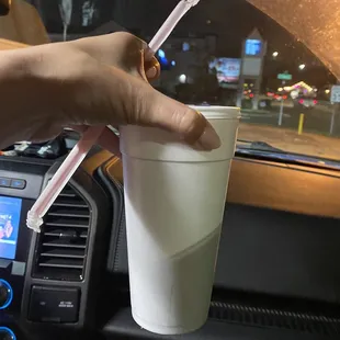 a hand holding a plastic cup in a car