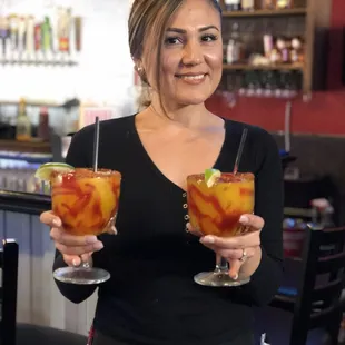  shows a woman holding two glasses of cocktails