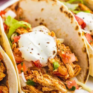 three chicken tacos on a white plate
