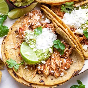 shredded chicken tacos with lime wedges