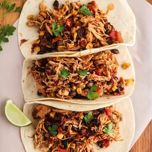 three pulled pork tacos on a cutting board