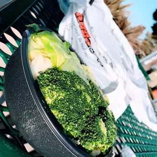 a bowl of broccoli on a bench