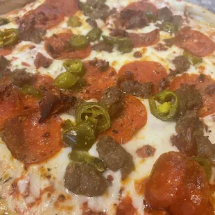 a pizza with pepperoni, sausage and jalapenos