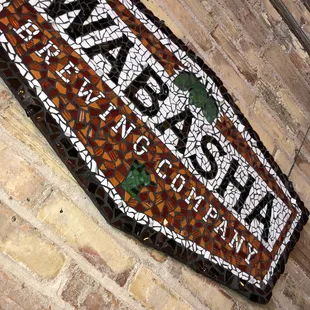 a mosaic sign on a brick wall