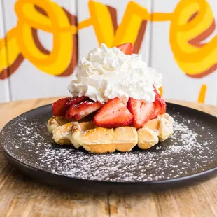 a waffle topped with whipped cream and strawberries