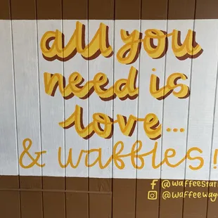 Painted wall sign says &quot;all you need is love...and waffles!&quot;