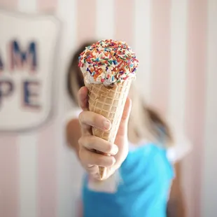 a woman holding a waffle cone with sprinkles