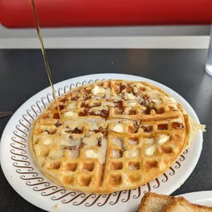 a waffle being drizzled with syrup