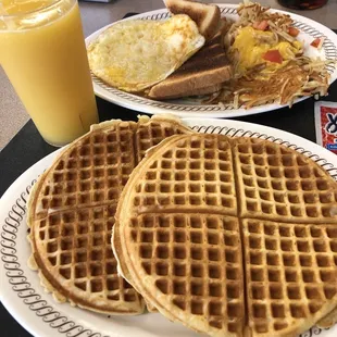 two plates of breakfast food and a glass of orange juice