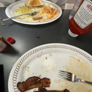 a plate of bacon, eggs, toast, and ketchup