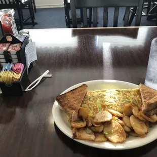 Omlet with cheese and green peppers, potatoes, and toast.