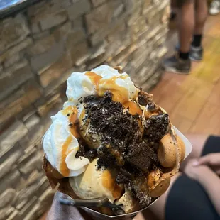 a person holding a waffle - licious ice cream sundae