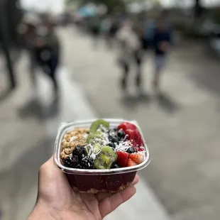a hand holding a bowl of fruit