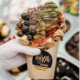 a hand holding a waffle with toppings