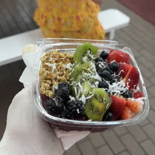 a hand holding a container of fruit