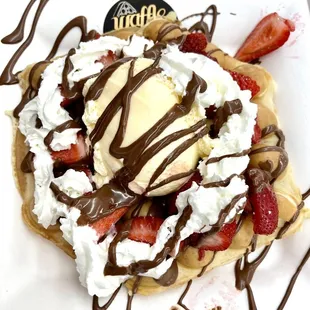a waffle topped with whipped cream, strawberries, and chocolate sauce