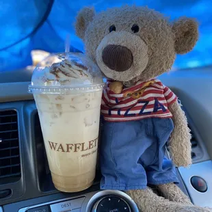 a teddy bear sitting on the dashboard of a car