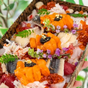 a person holding a box of sushi