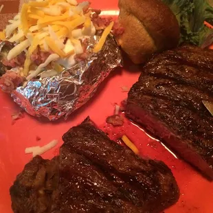 NY strip cooked medium rare with loaded baked potato and whole wheat muffin bread