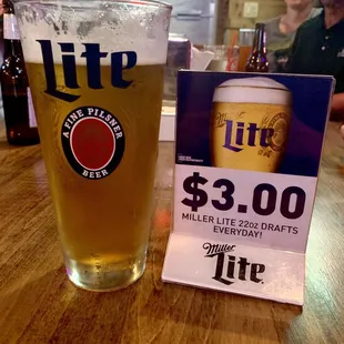 a glass of lite beer and a price card