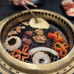 a person using tongs to grill vegetables