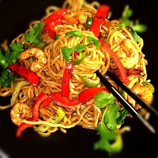 a plate of noodles with shrimp and vegetables