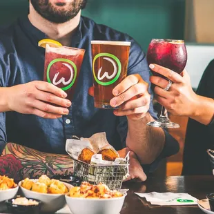 two people holding glasses of beer