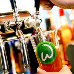 a person filling a pint of beer