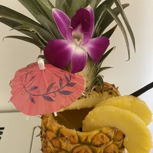 a pineapple with a purple flower and an umbrella