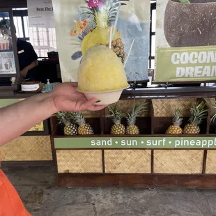 a person holding a pineapple ice cream cone