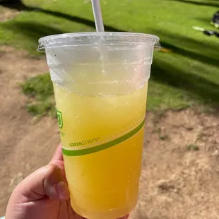 a hand holding a cup of juice