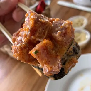 a close up of a person holding a piece of meat with chopsticks