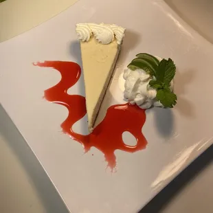 a slice of cheesecake with whipped cream and a sprig of mint