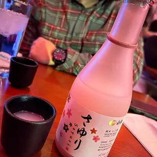 a man sitting at a table with a bottle of sake