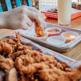 a person picking a piece of fried chicken