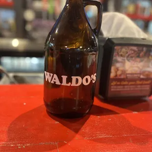a large brown growler bottle on a red table
