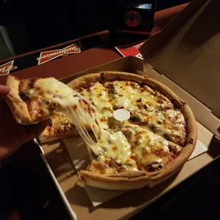 a hand holding a slice of pizza