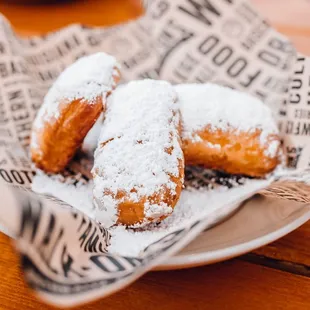 a basket of powdered sugared doughnuts