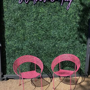 two pink chairs in front of a green wall