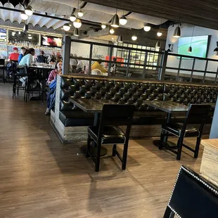 Towards the bar with empty tables and people waiting.