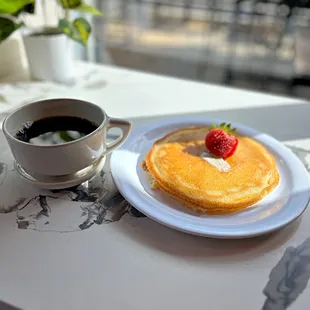 a plate of pancakes and a cup of coffee