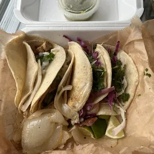 Chicken and shrimp tacos with cilantro, red cabbage, onions, limes, and a side of green sauce