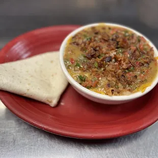 a bowl of soup and a cracker on a red plate