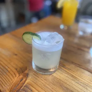 a drink with a slice of cucumber on the rim