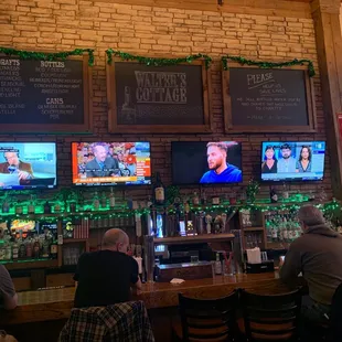 people sitting at a bar watching tvs