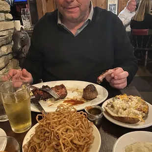 My handsome husband with the onion straws, his filet and ribs and a loaded baked potato
