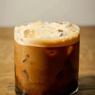 a glass of iced coffee on a wooden table