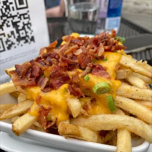 a plate of french fries with bacon and cheese